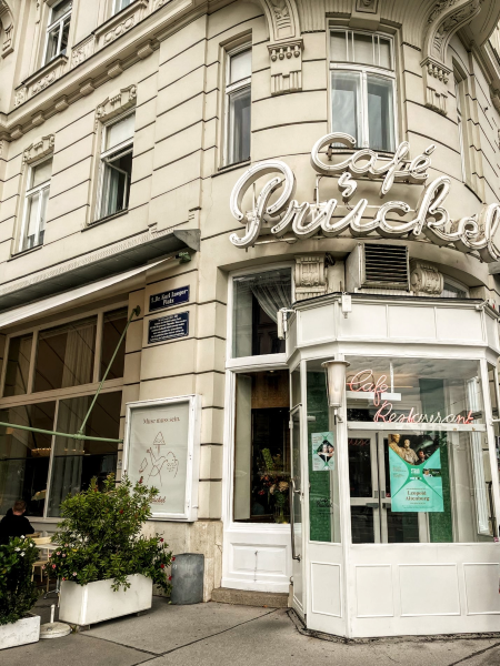 Storefront for Café Prückel in Vienna, with its name in neon lights in a script typeface.